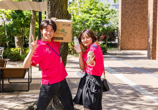オープンキャンパスで笑顔でポーズをとる学生スタッフ